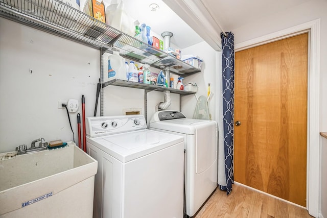 washroom with a sink, independent washer and dryer, laundry area, and light wood-type flooring