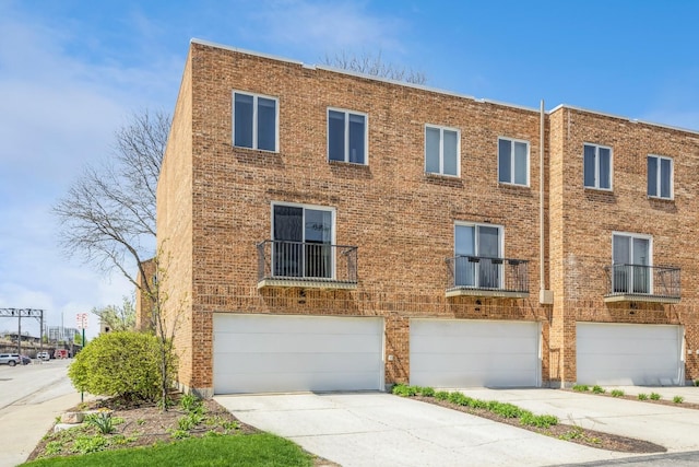 multi unit property with driveway, brick siding, and an attached garage