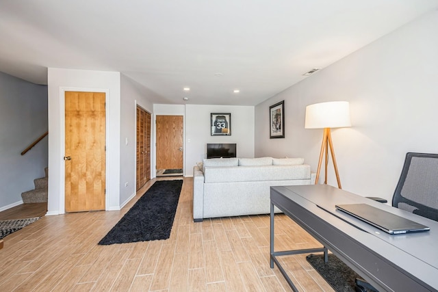living area featuring baseboards, recessed lighting, light wood-type flooring, and stairway