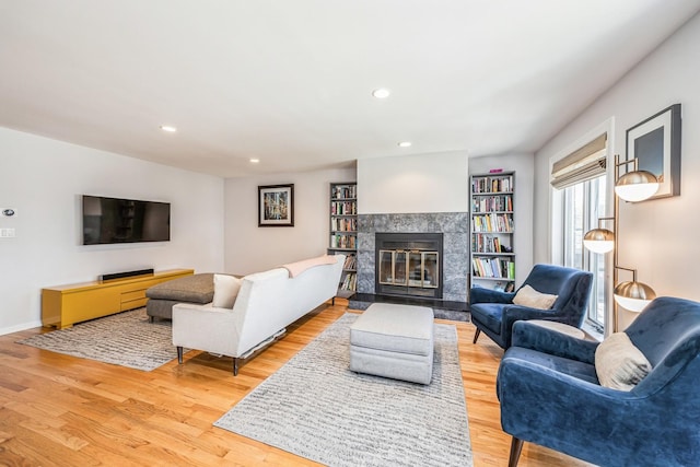 living area featuring light wood finished floors, recessed lighting, baseboards, and a fireplace