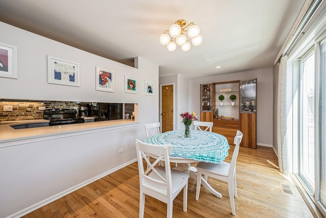 dining area with visible vents, a chandelier, light wood finished floors, and baseboards