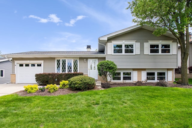 split level home with an attached garage, concrete driveway, a front yard, and brick siding