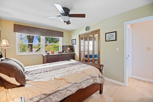 bedroom with light wood-style flooring, baseboards, a ceiling fan, and access to outside