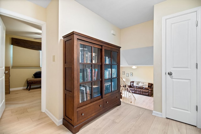 hallway featuring light wood finished floors and baseboards
