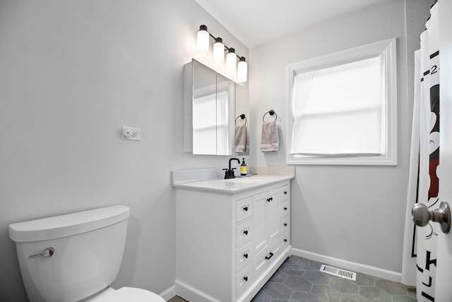 bathroom featuring toilet, baseboards, and vanity