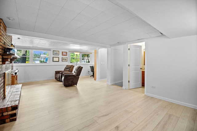 sitting room with a fireplace, light wood finished floors, and baseboards