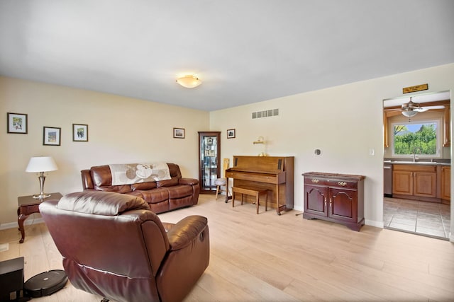 living room featuring light wood-style flooring, a ceiling fan, and baseboards