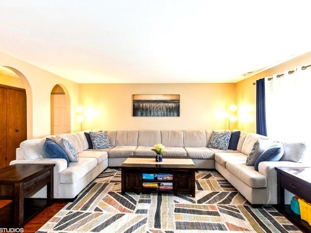 living area with arched walkways and wood finished floors
