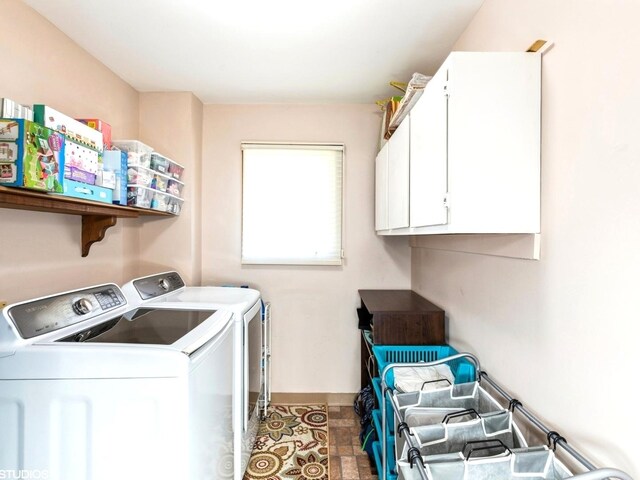 washroom featuring washing machine and clothes dryer, cabinet space, and baseboards