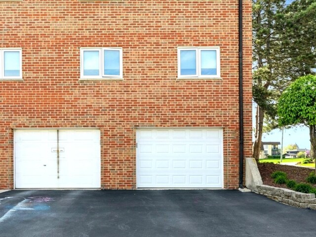 view of side of property featuring a garage, driveway, and brick siding