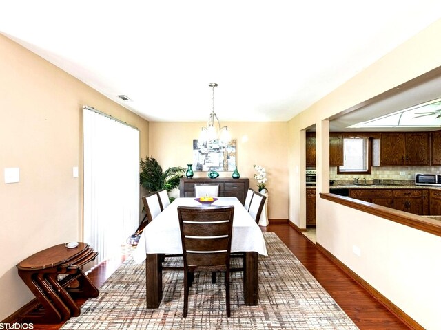 dining space with a chandelier, dark wood-style floors, and baseboards