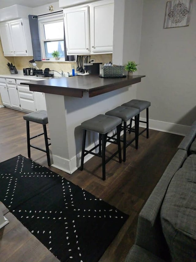 475 Laurel St, Elgin, IL 60120 - kitchen featuring a breakfast bar, white cabinetry, baseboards, dark wood finished floors, and a peninsula