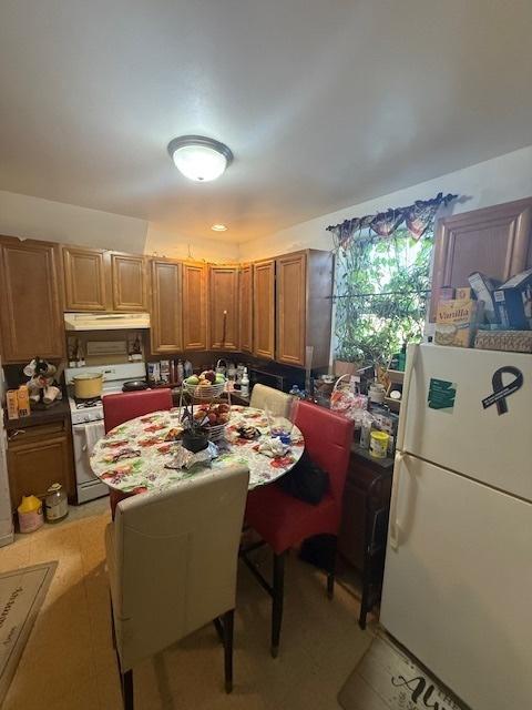 kitchen featuring brown cabinetry, white appliances, and under cabinet range hood