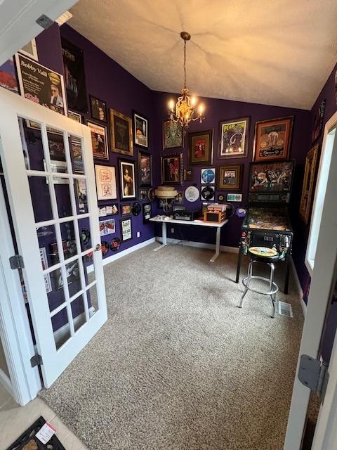 carpeted home office featuring a chandelier, baseboards, and vaulted ceiling