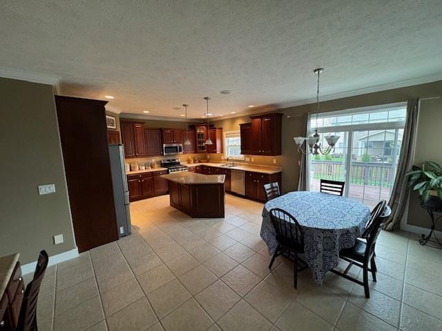 kitchen featuring a chandelier, light tile patterned floors, stainless steel appliances, a kitchen island, and ornamental molding