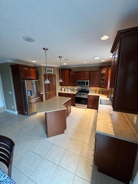kitchen with light tile patterned floors, a center island, a sink, and appliances with stainless steel finishes