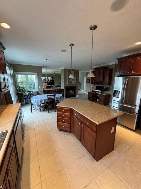 kitchen featuring light tile patterned floors, stainless steel appliances, decorative light fixtures, light countertops, and a kitchen island