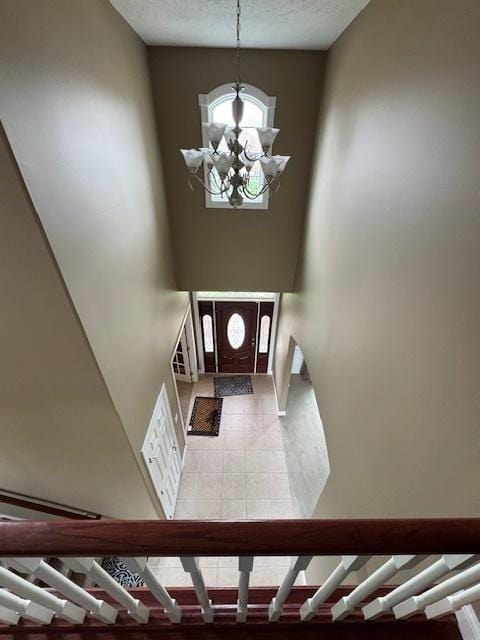 entryway featuring light tile patterned floors, a notable chandelier, and baseboards