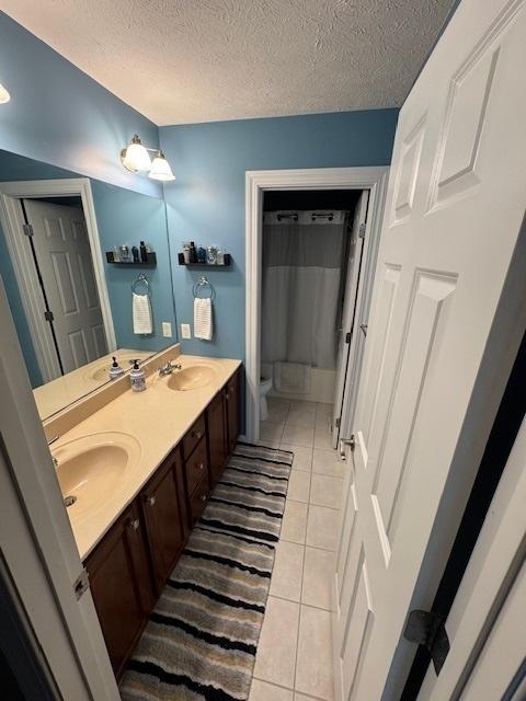 full bathroom with tile patterned floors, toilet, double vanity, and a sink