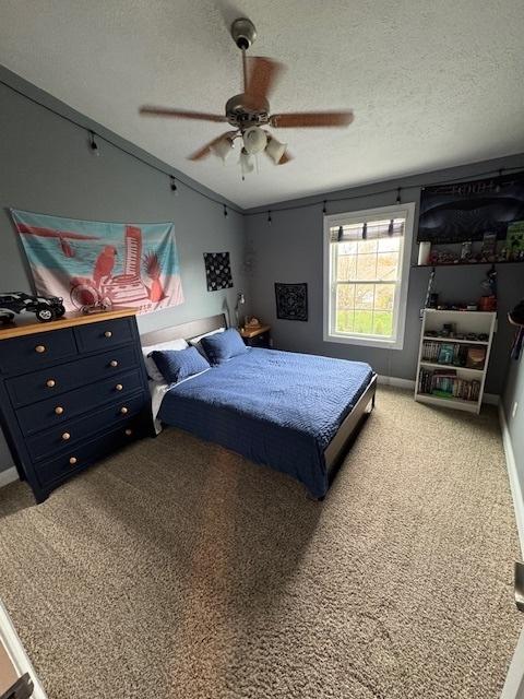 bedroom featuring a textured ceiling, carpet flooring, and a ceiling fan