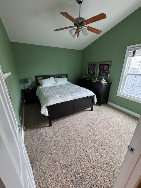 bedroom with light colored carpet, ceiling fan, lofted ceiling, and baseboards