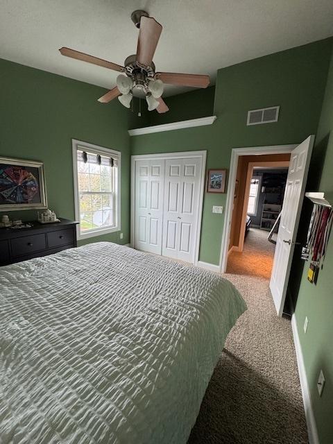 carpeted bedroom with a closet, multiple windows, visible vents, and baseboards