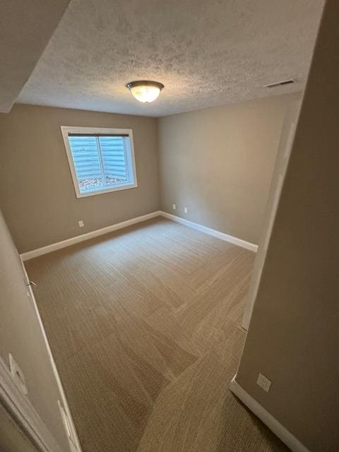 unfurnished room with baseboards, carpet floors, and a textured ceiling