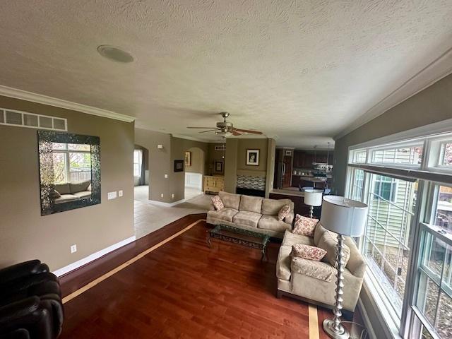 living area with a textured ceiling, visible vents, wood finished floors, and a healthy amount of sunlight