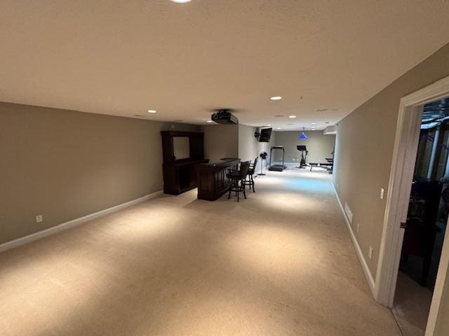 interior space with baseboards, bar, and light colored carpet