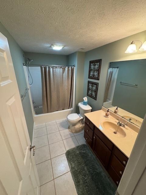 bathroom with a textured ceiling, shower / bath combo with shower curtain, toilet, tile patterned floors, and vanity