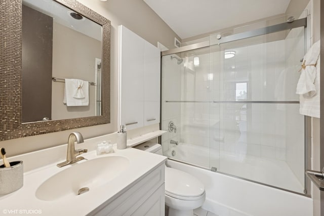 bathroom featuring vanity, combined bath / shower with glass door, and toilet