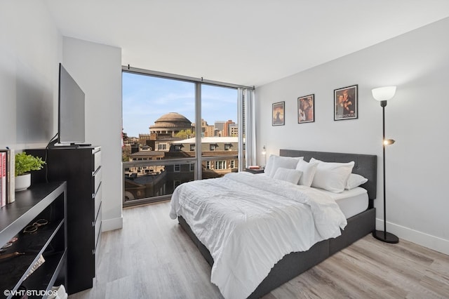 bedroom with baseboards, floor to ceiling windows, and light wood finished floors