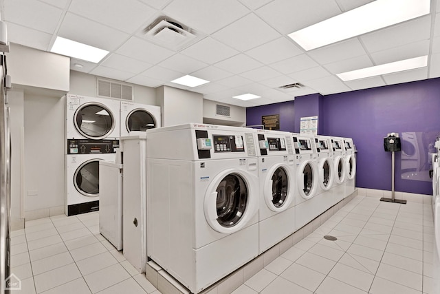community laundry room featuring stacked washing maching and dryer, washing machine and dryer, light tile patterned floors, and visible vents