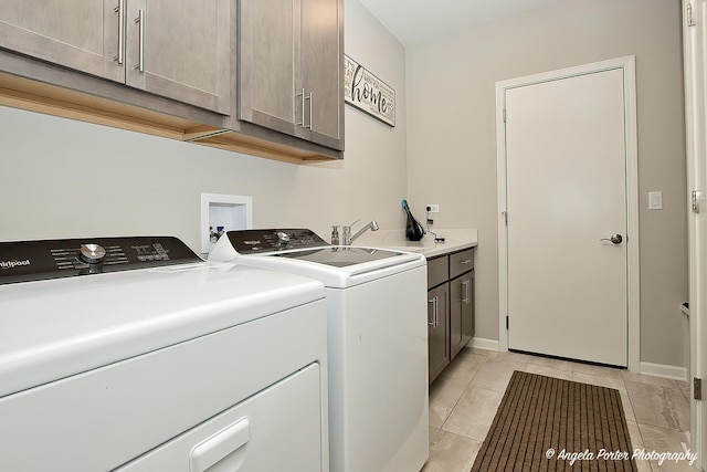 clothes washing area with a sink, washing machine and dryer, cabinet space, and baseboards