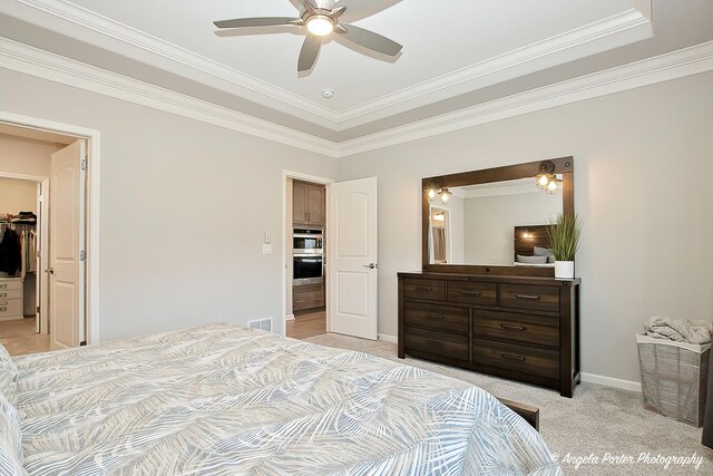 bedroom featuring a walk in closet, visible vents, crown molding, and light colored carpet