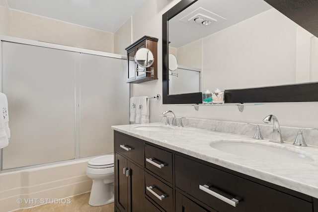 bathroom featuring toilet, double vanity, and shower / bath combination with glass door