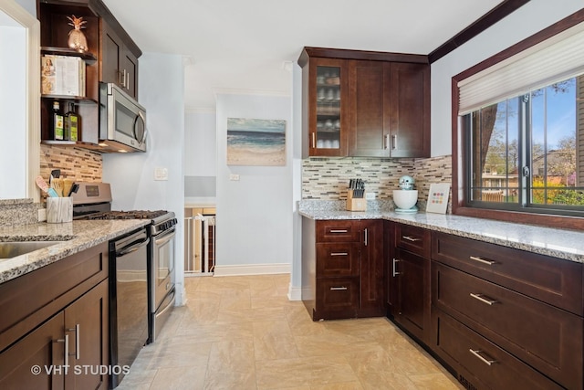 kitchen with stainless steel appliances, light stone counters, backsplash, and glass insert cabinets