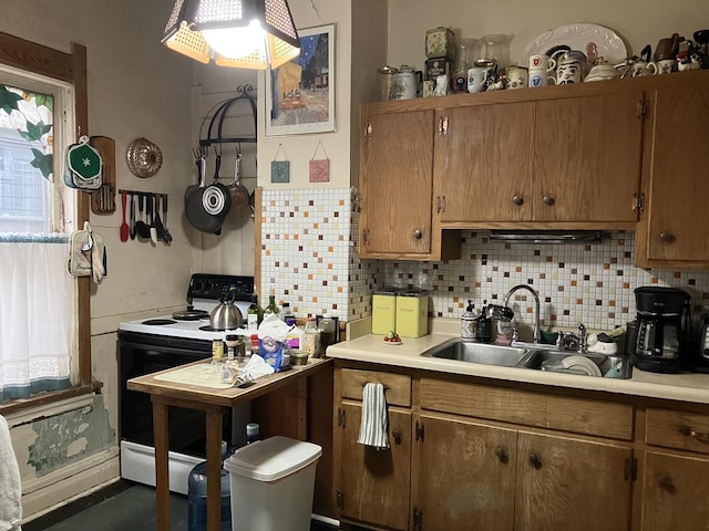 kitchen featuring brown cabinetry, decorative backsplash, range with electric stovetop, light countertops, and a sink