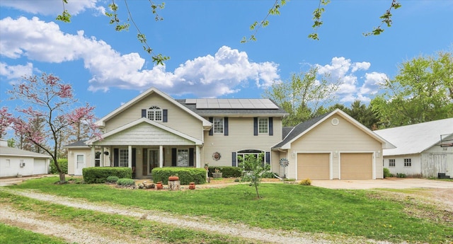 view of front facade featuring covered porch, a front yard, roof mounted solar panels, an attached garage, and driveway