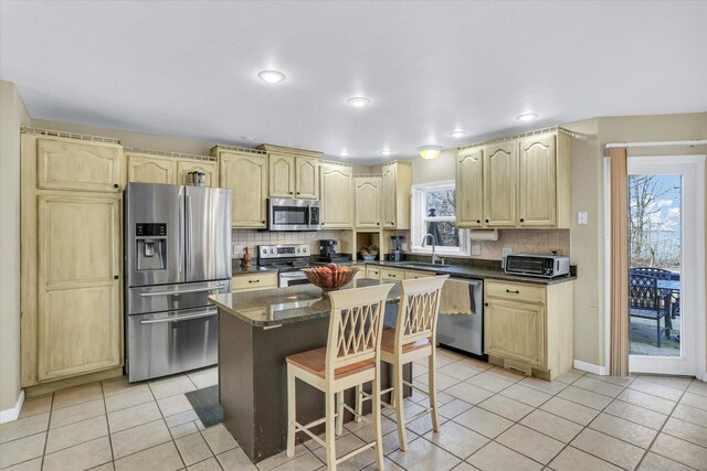kitchen featuring decorative backsplash, a sink, light brown cabinets, and stainless steel appliances