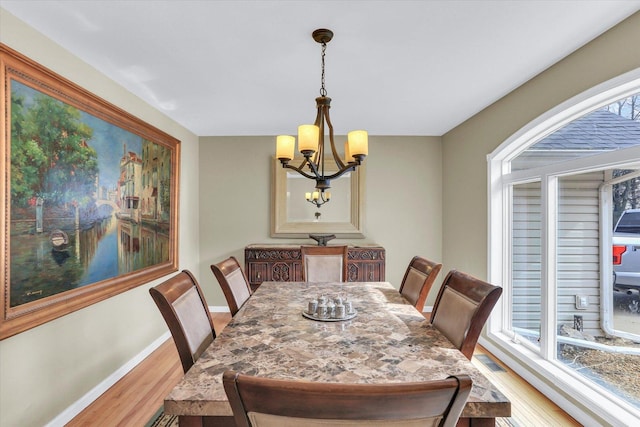 dining room with plenty of natural light, light wood finished floors, baseboards, and a chandelier