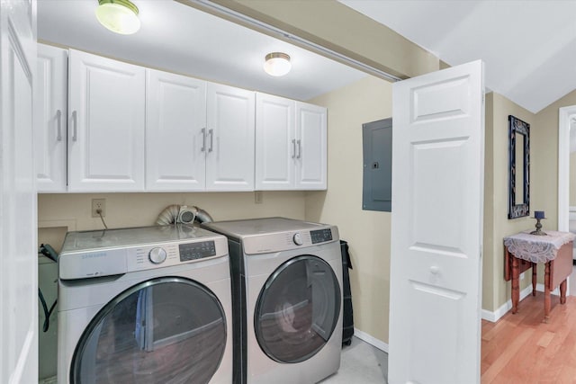 washroom featuring baseboards, light wood-type flooring, electric panel, separate washer and dryer, and cabinet space