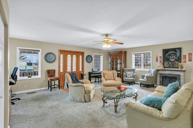 carpeted living room with ceiling fan, visible vents, baseboards, and a fireplace