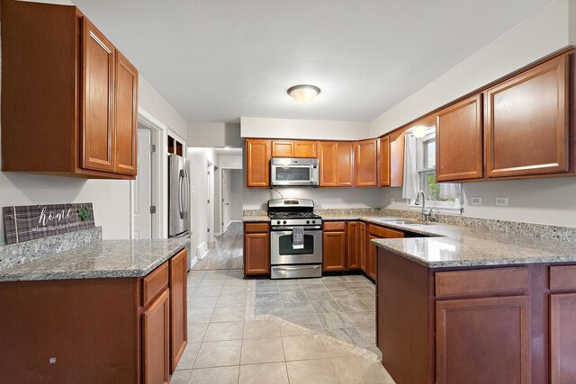 15058 Tripp Ave, Midlothian, IL 60445 - kitchen featuring stainless steel appliances, a sink, brown cabinetry, light stone counters, and a peninsula