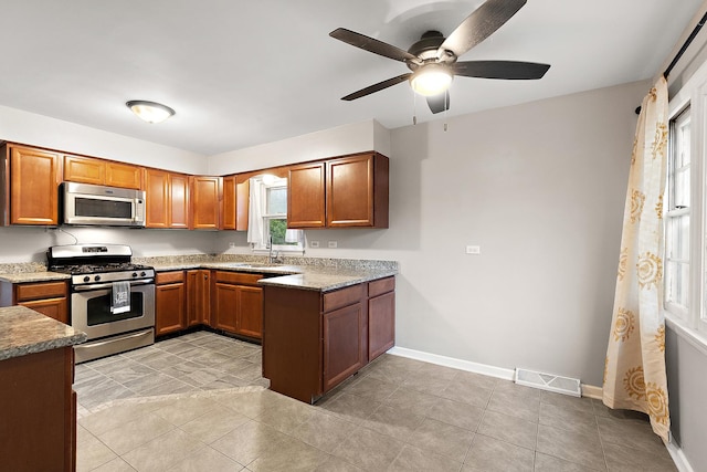15058 Tripp Ave, Midlothian, IL 60445 - kitchen featuring stainless steel appliances, a sink, brown cabinets, ceiling fan, and baseboards
