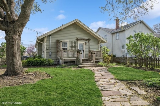 view of front of home with fence, a wooden deck, and a front yard