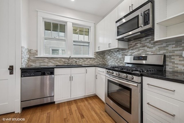 kitchen with backsplash, stainless steel appliances, white cabinetry, and a sink