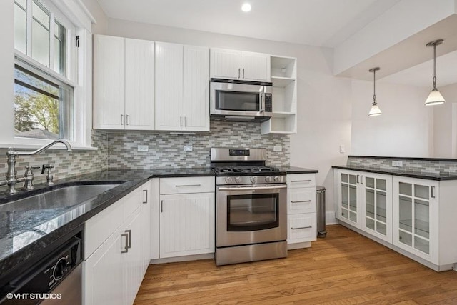 kitchen featuring tasteful backsplash, a sink, white cabinets, stainless steel appliances, and light wood-style flooring