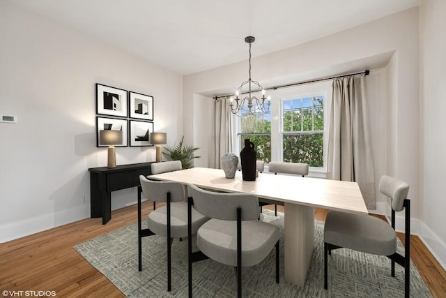 dining area featuring an inviting chandelier, baseboards, and light wood finished floors
