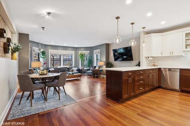 kitchen with stainless steel dishwasher, a peninsula, light wood-style floors, light countertops, and white cabinets